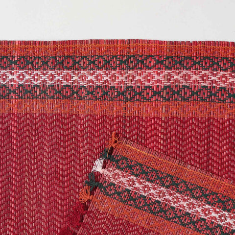 Detailed close-up of a red Madhurkathi placemat showcasing the dense natural fibre weave, geometric pattern, and durable stitched border