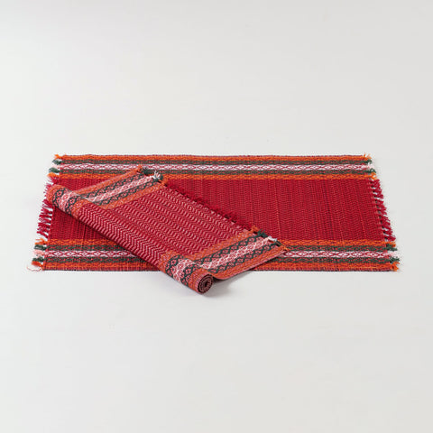 Handwoven red Madhurkathi placemat set crafted from natural river grass with green, white, and orange border accents