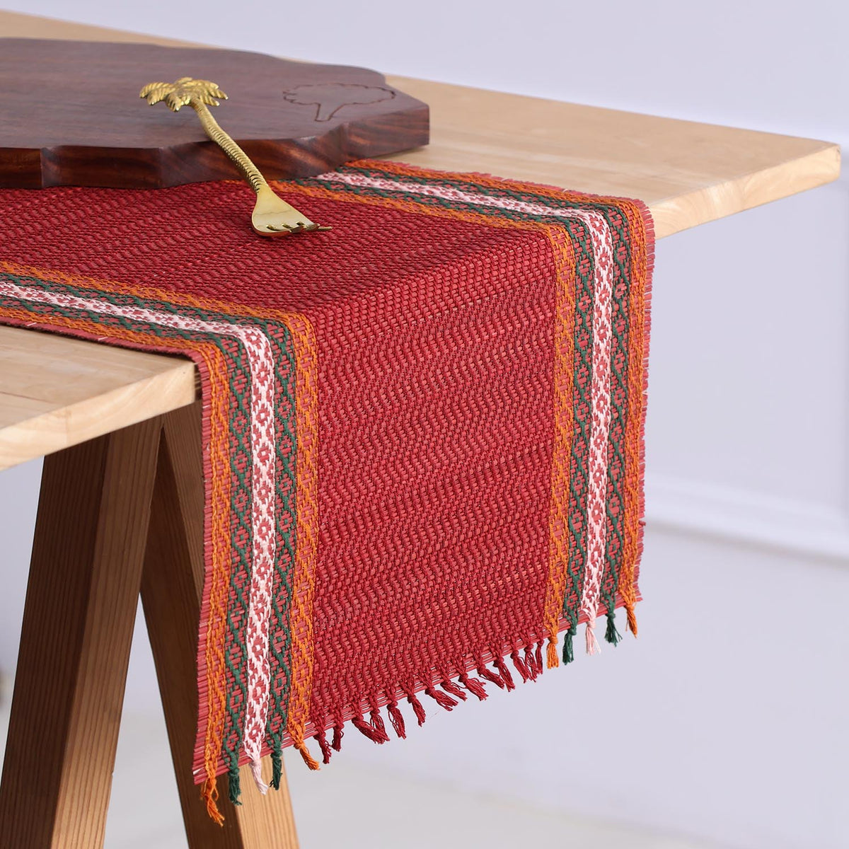 Handmade red Madurkathi table runner styled on a dining table, highlighting the natural river grass weave, colourful borders, and elegant table setting