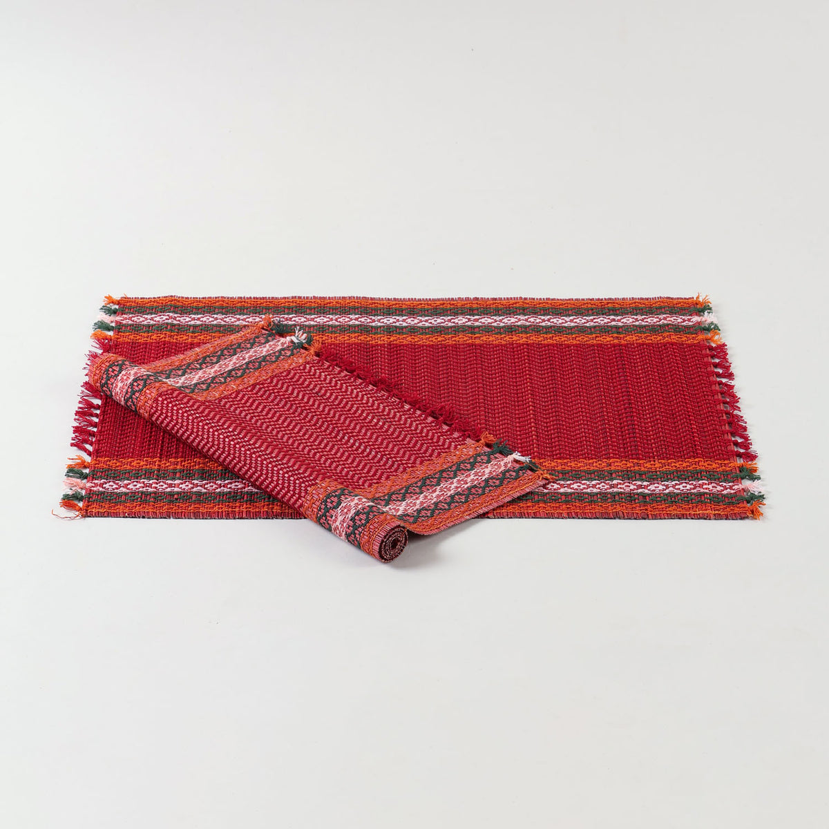 Handwoven red Madurkathi placemat set crafted from natural river grass with green, white, and orange border accents