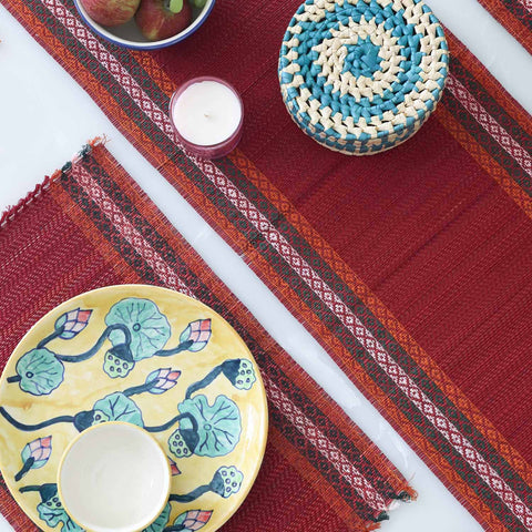 Dining table setting with a red Madurkathi table runner and placemats set featuring natural river grass weave and handcrafted table decor