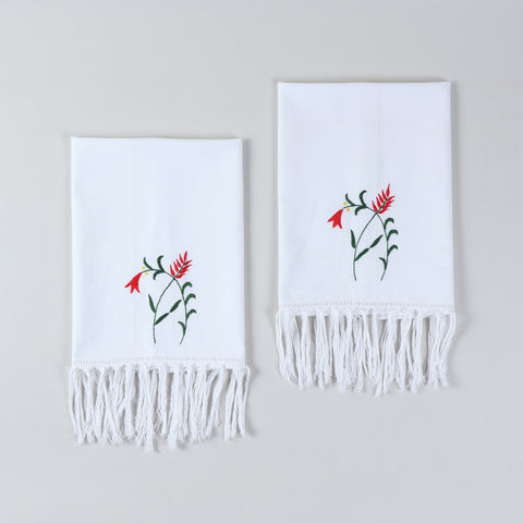 Set of two white cotton kitchen towels featuring red penstemon floral embroidery and tasselled edges
