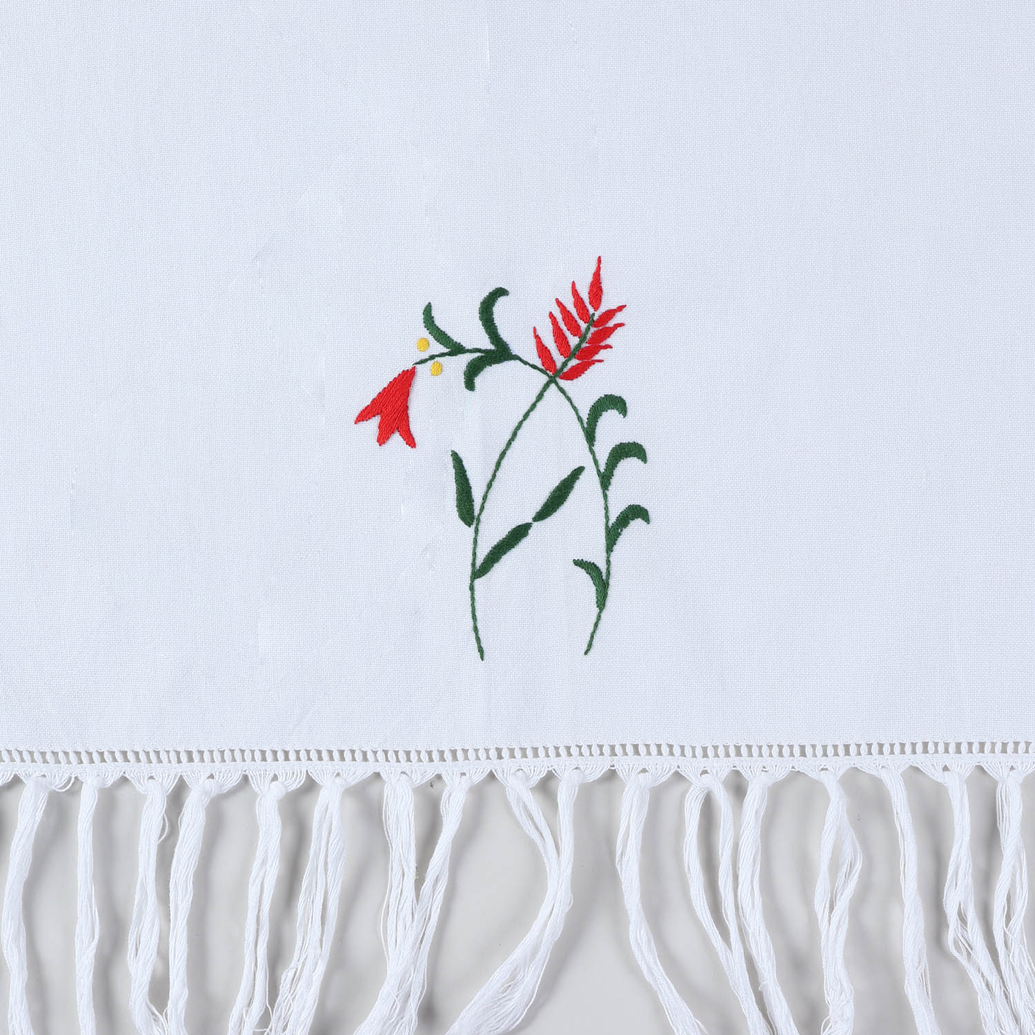 Close-up of red penstemon floral hand embroidery and textured tassel fringe on cotton kitchen towel