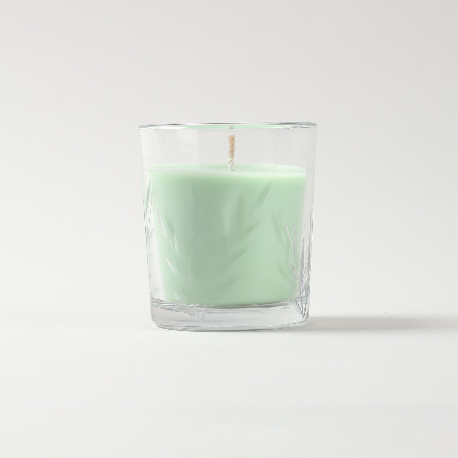 Green apple scented candle in a green glass jar featuring a decorative leaf pattern and soy wax