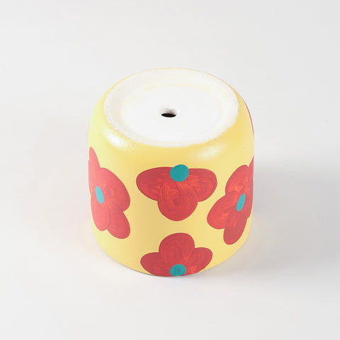 Hand-painted ceramic cylinder planter pot flipped upside down to show a built-in central drainage hole for proper water flow and plant health.