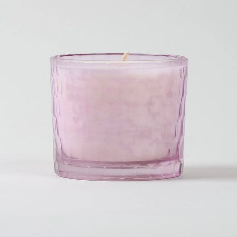 Eye-level view of a rose scented soy wax candle highlighting the textured glass holder and handcrafted finish
