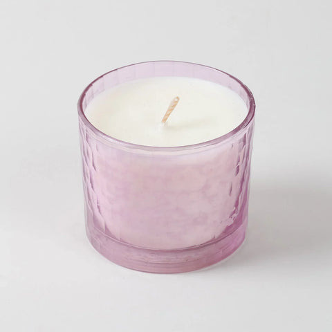 Front view of a rose scented soy wax candle in a decorative pink chiseled glass holder
