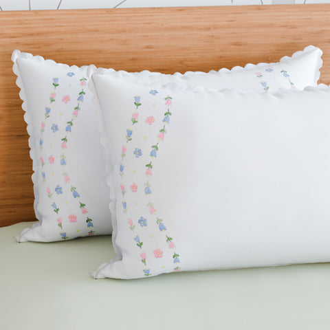 Rose vine embroidered pillow cases styled on a bed adding a handcrafted touch to elegant bedroom decor