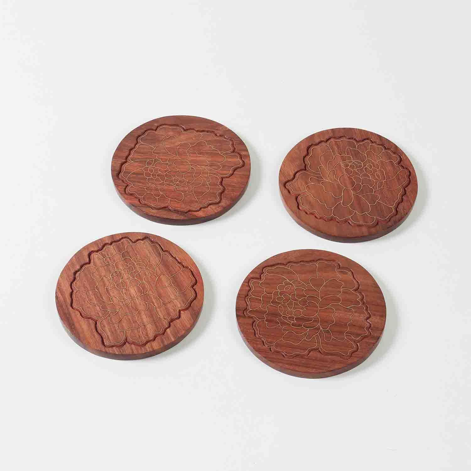 Set of four handcrafted rosewood coasters featuring marigold floral brass inlay displayed against a clean background