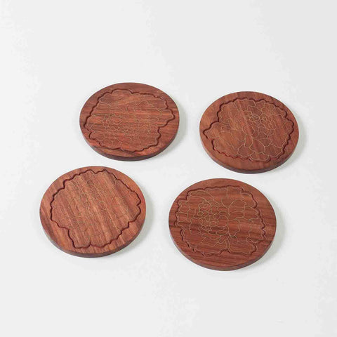 Set of four handcrafted rosewood coasters featuring marigold floral brass inlay displayed against a clean background