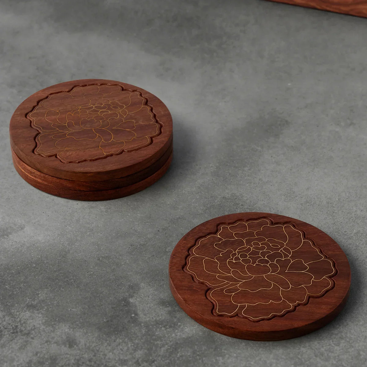 Rosewood coaster set with marigold floral brass inlay, styled on a table top making an elegant corporate gift