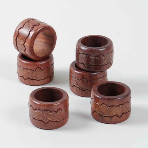 Side view of stacked  six round wooden napkin rings, highlighting lotus inspired brass detailing and smooth craftsmanship