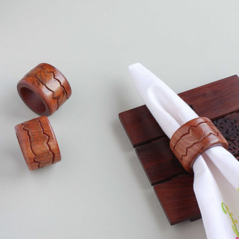 Round wooden napkin rings with lotus brass inlay styled on a dining table for elegant table setting decor