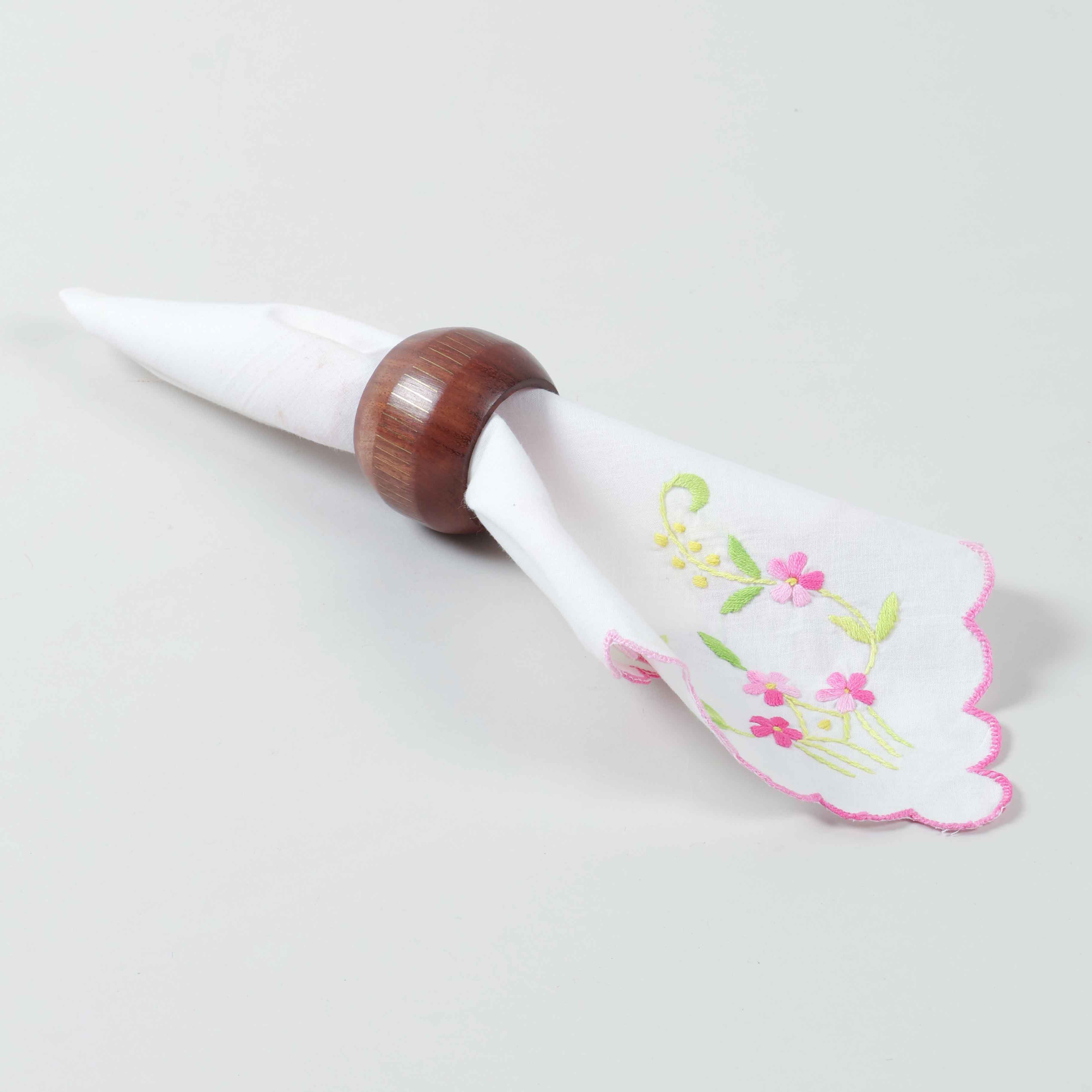 Handcrafted round wooden napkin ring holding a folded table napkin for refined dining table styling