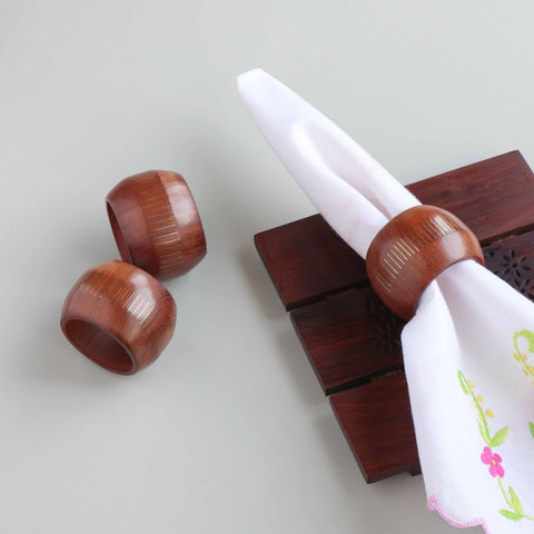 Round wooden napkin rings with brass inlay styled on a dining table for an elegant table setting decor