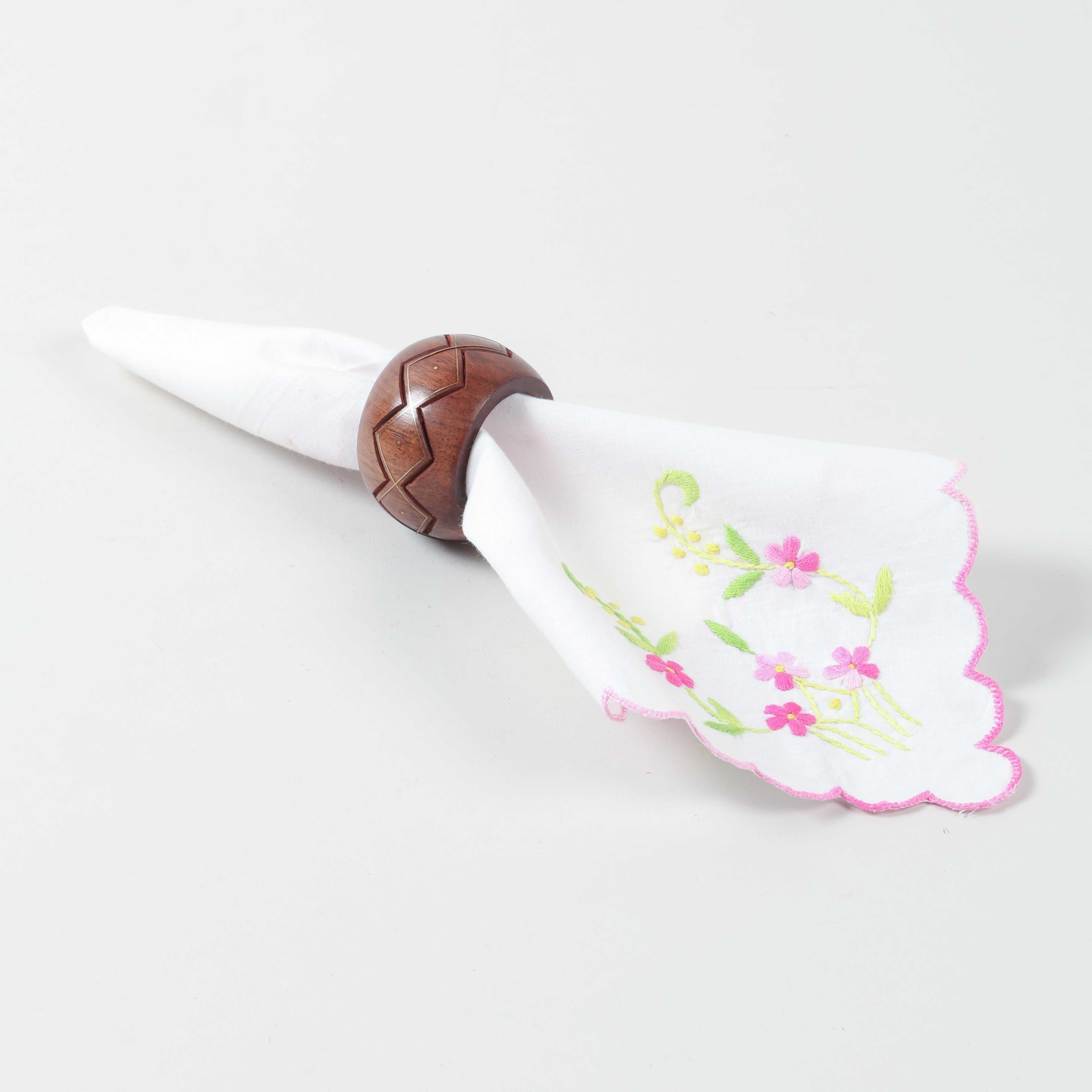 Handmade round wooden napkin ring with brass inlay holding a folded cloth napkin for table styling
