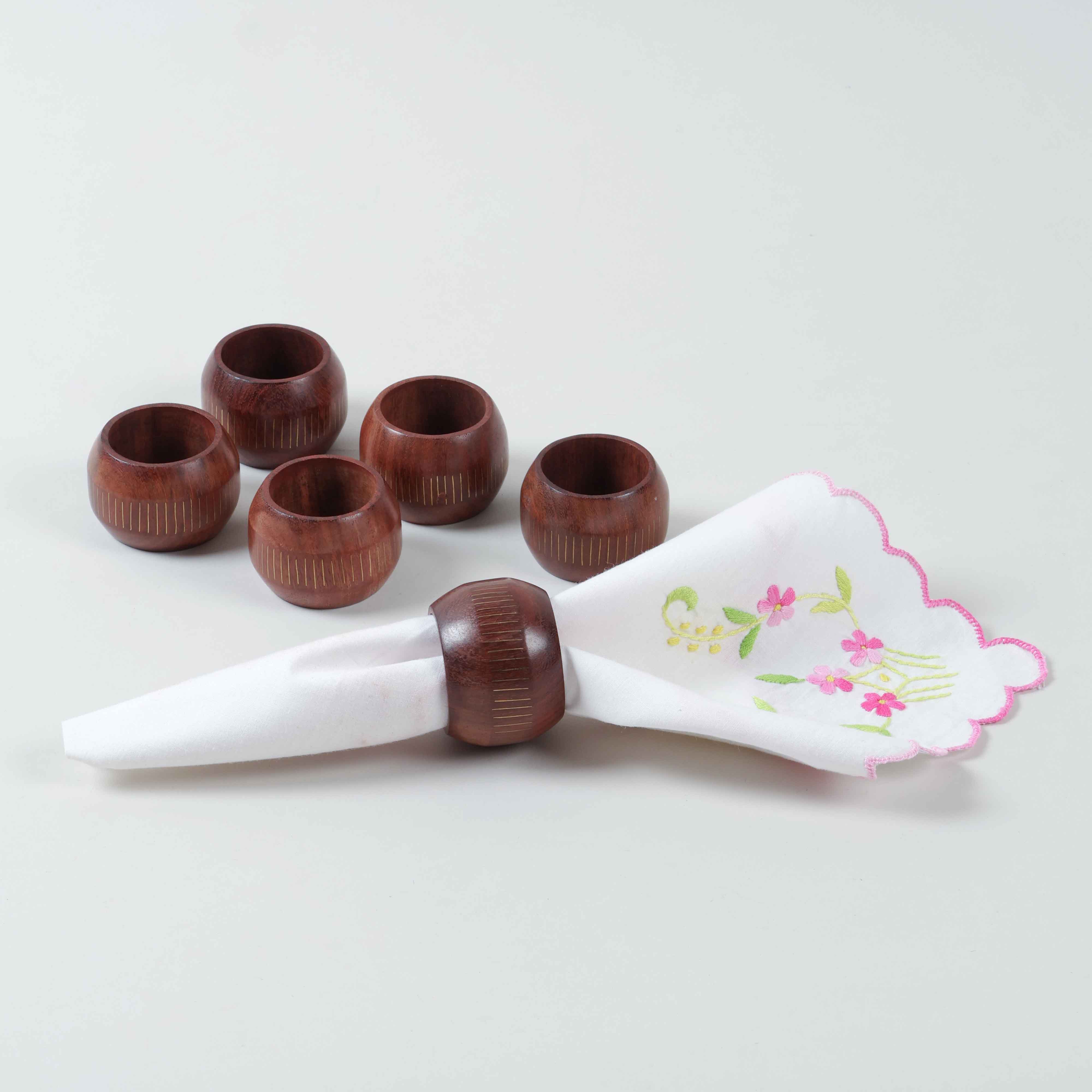 Set of 6 handmade round wooden napkin rings handcrafted with Tarkashi brass inlay for elegant dining table decor, with one styled with napkin