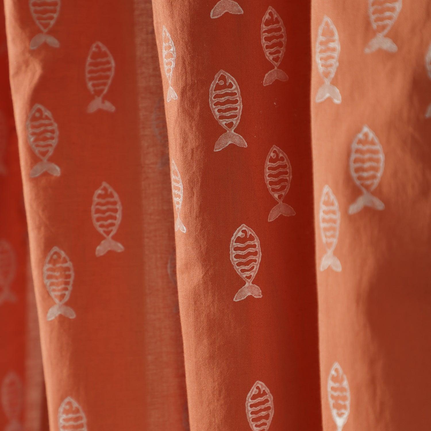 Close-up of the hand block printed fish pattern on soft rust mulmul cotton curtain fabric