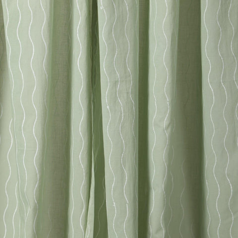 Close-up of the hand block printed wave pattern on soft sage green mulmul cotton curtain fabric.