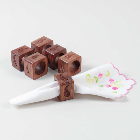 Handcrafted set of 6 paisley wooden napkin rings, with one holding a folded table napkin for sophisticated dining table styling