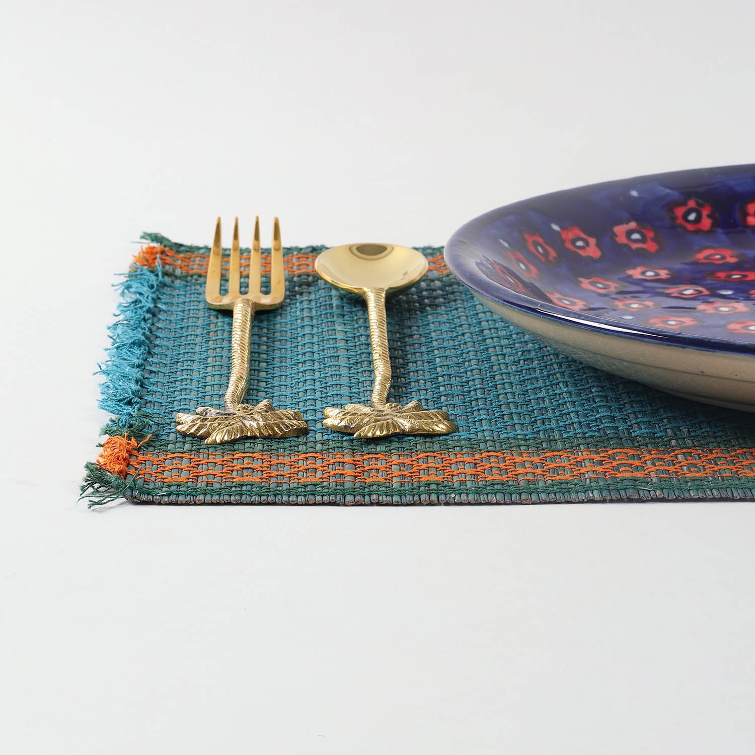Handmade blue Madurkathi placemat styled on a dining table with tableware, showcasing natural fibre texture and elegant table setting