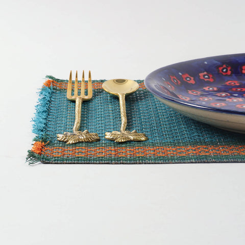 Handmade blue Madurkathi placemat styled on a dining table with tableware, showcasing natural fibre texture and elegant table setting