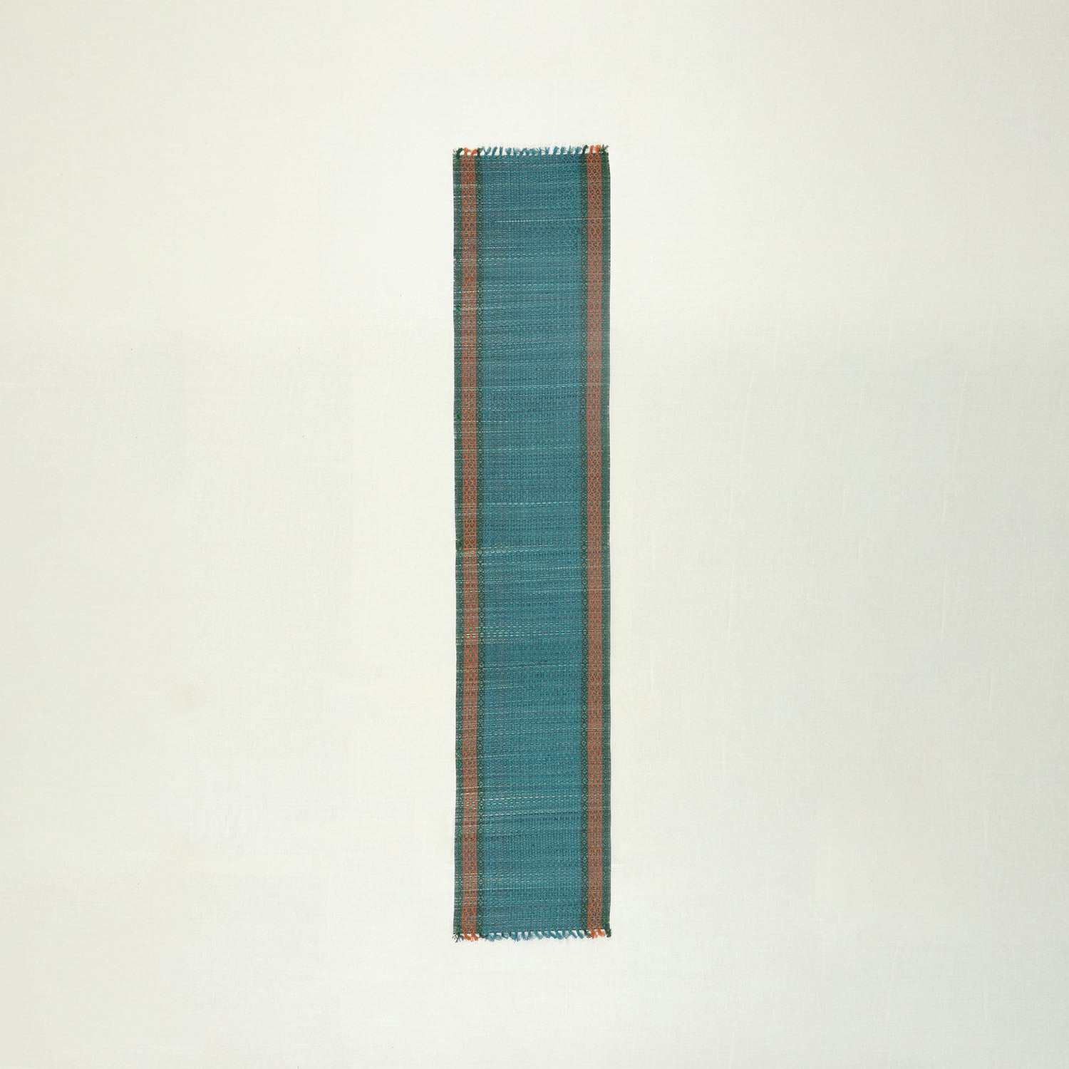 Full view of a handmade blue Madurkathi runner on a plain background, showcasing natural river grass weaving and colourful border detailing
