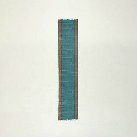 Full view of a handmade blue Madurkathi runner on a plain background, showcasing natural river grass weaving and colourful border detailing