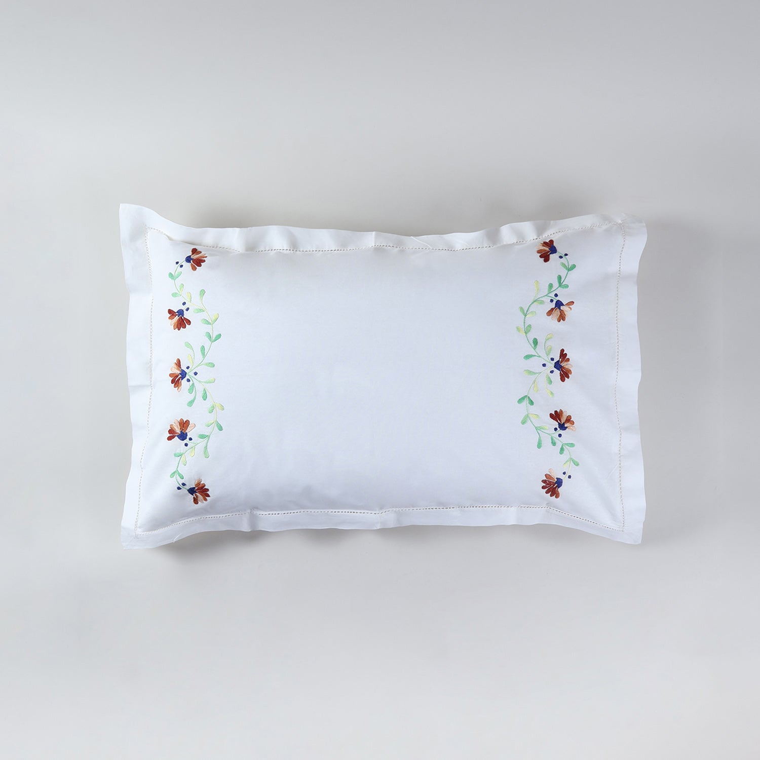 White cotton pillow case adorned with brown floral vine embroidery and subtle green accents