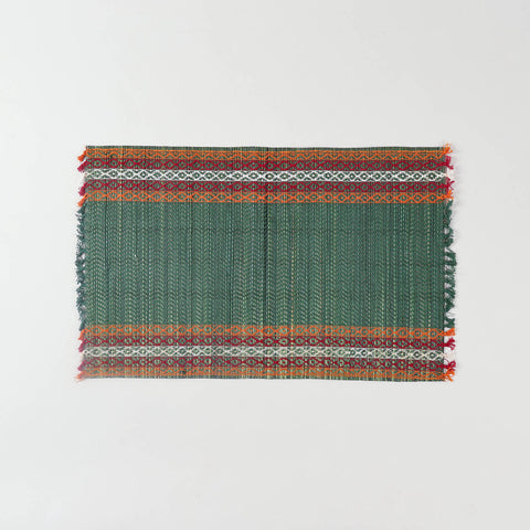 Full view of a handmade green Madurkathi placemat on a plain background, showcasing natural river grass weaving and colourful border detailing