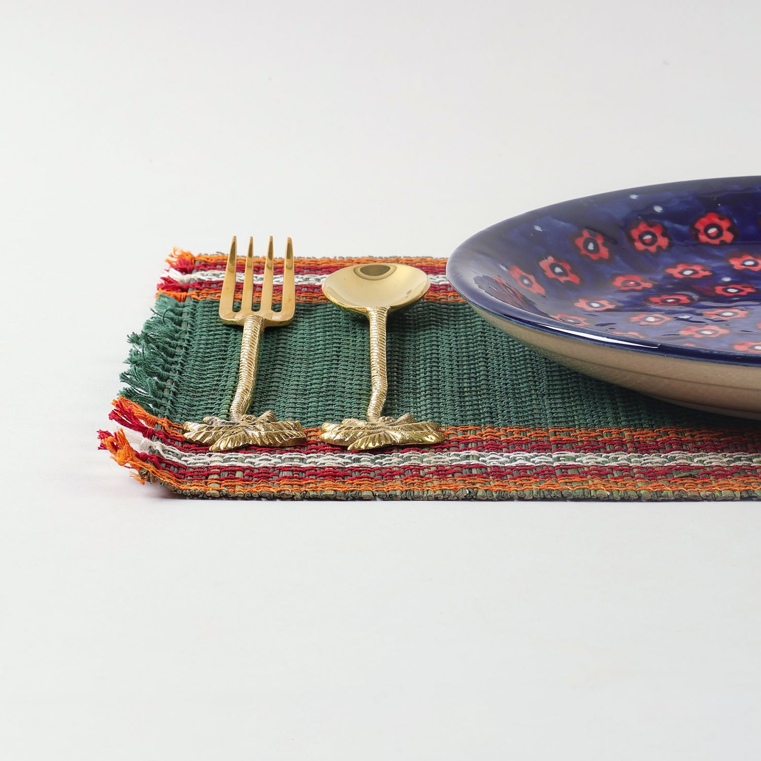 Handmade green Madurkathi placemat styled on a dining table with tableware, showcasing natural fibre texture and elegant table setting