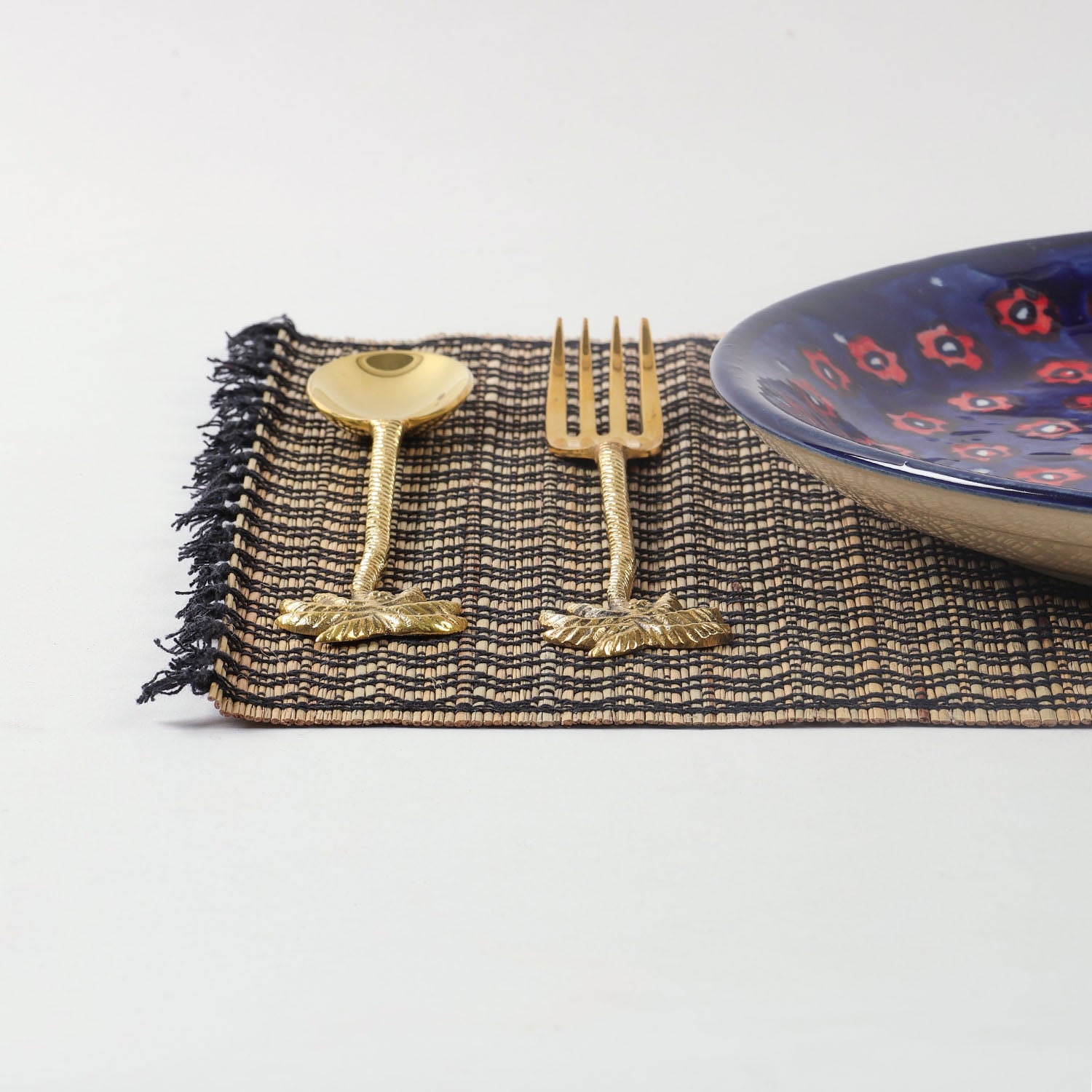 Handmade Madurkathi placemat styled on a dining table with dinnerware, showcasing natural fibre texture and an elegant table setting