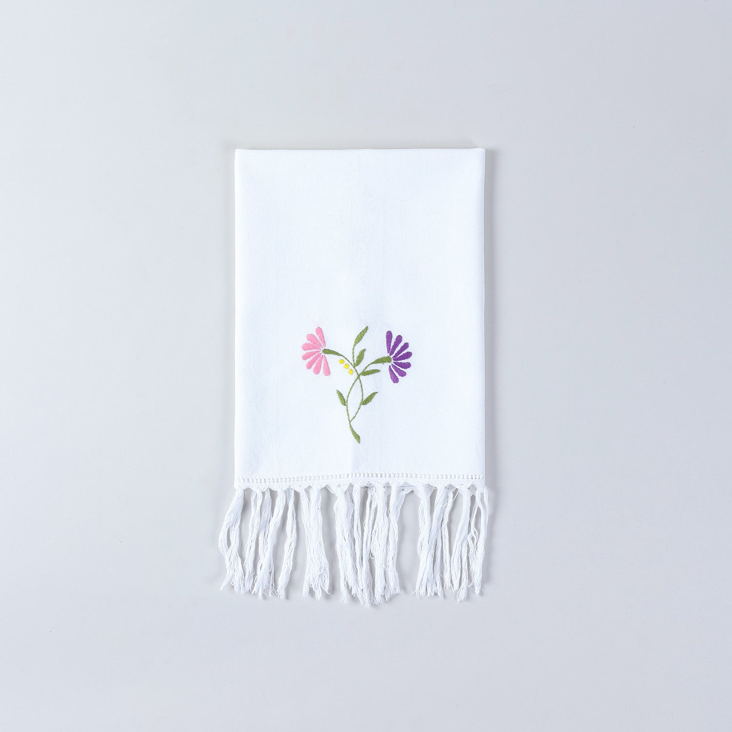White cotton kitchen towel decorated with pink and purple floral embroidery and handcrafted detailing
