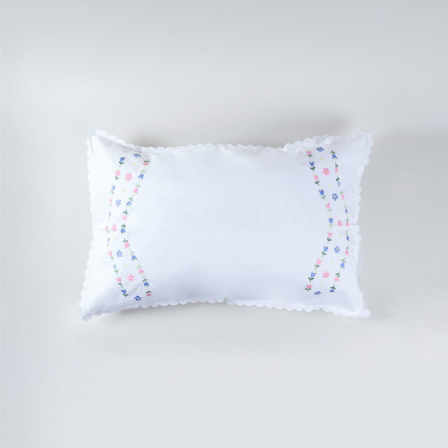 White cotton pillow case with embroidered rose vine motifs arranged along both edges for a framed look