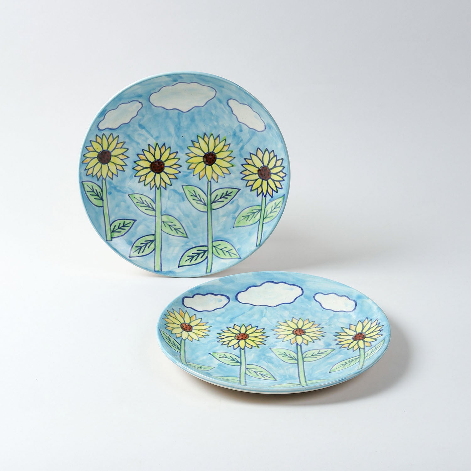 Handmade ceramic dinner plates featuring sunflower motifs on a blue background, crafted in Khurja,