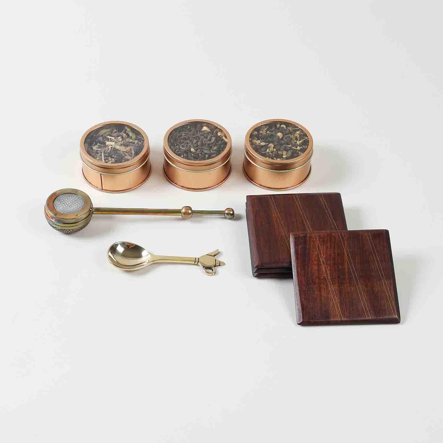 Tea gift hamper contents including tea blends tea brewer brass spoon and wooden coaster set