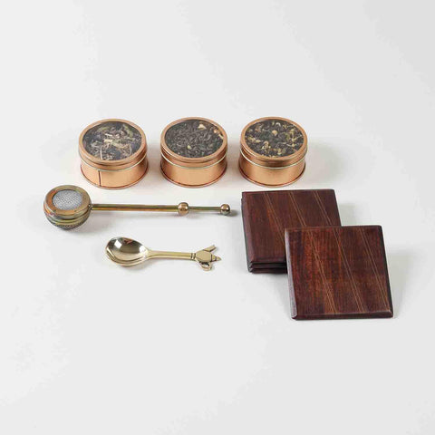 Tea gift hamper contents including tea blends tea brewer brass spoon and wooden coaster set