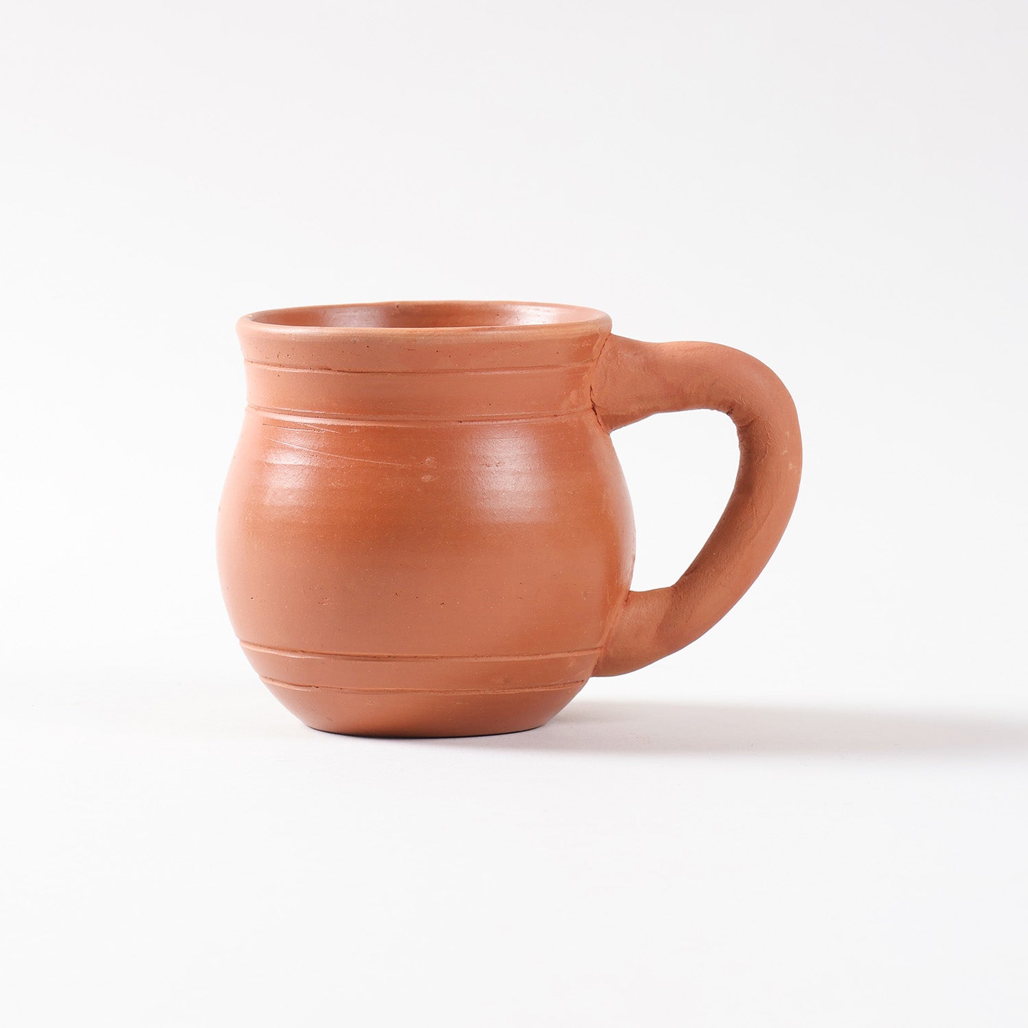 Side profile of a handmade terracotta tea cup showcasing traditional pottery craftsmanship and natural earthen texture