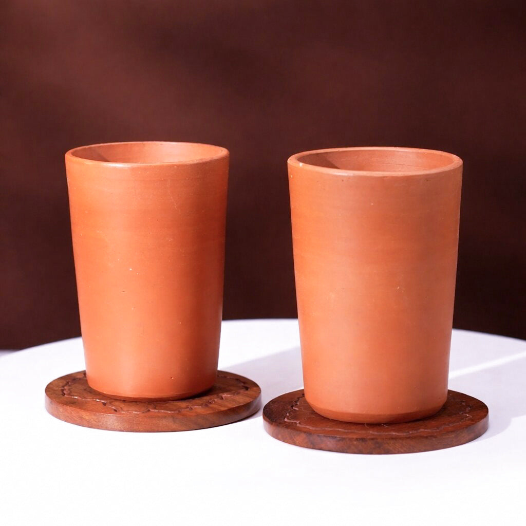 Handmade terracotta water tumblers set on wooden coasters for sustainable table setting and everyday drinkware