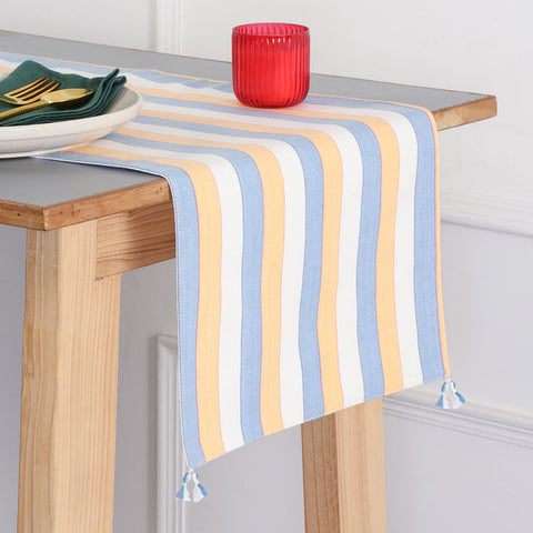 Handwoven cotton table runner with blue, orange, and white striped pattern and tassels styled on a dining table, creating a vibrant table setting and dining table décor