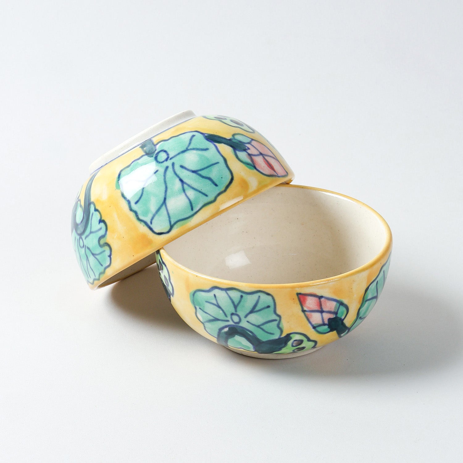 Hand-painted Water Lily ceramic katori set with one bowl upright and another resting upside down at an angle, highlighting handcrafted Khurja ceramic detailing