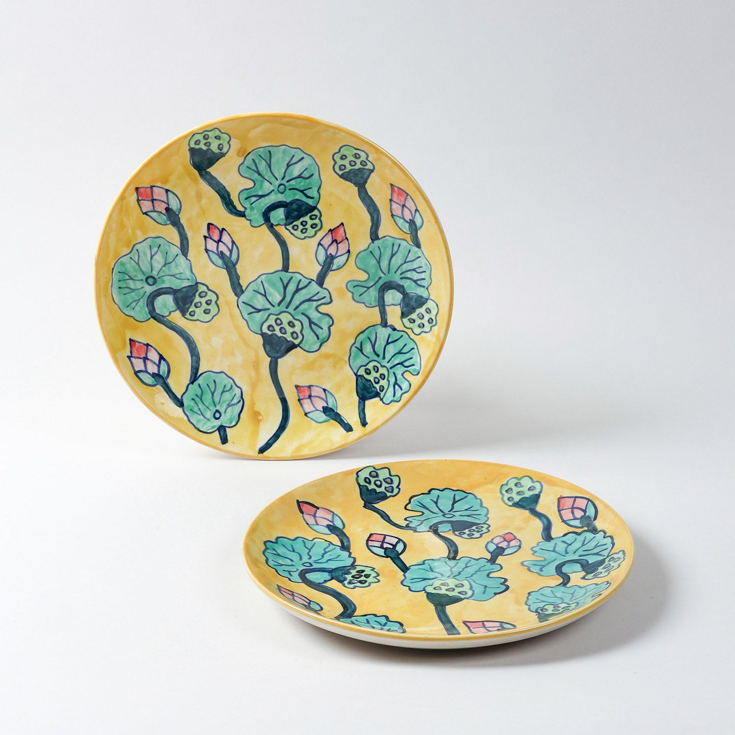 Handmade ceramic dinner plates featuring water lily motifs on a yellow base, crafted in Khurja and styled for table settings