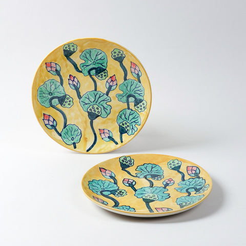 Handmade ceramic dinner plates featuring water lily motifs on a yellow base, crafted in Khurja and styled for table settings