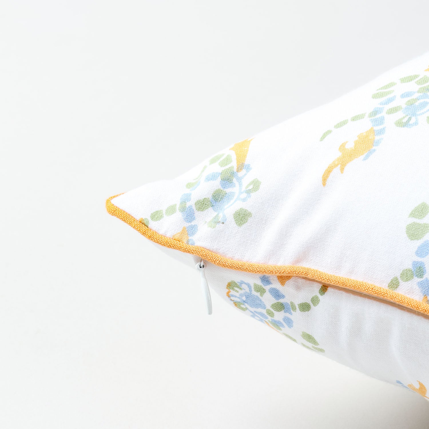 Orange, green, and blue swirl print detail on a white cotton cushion cover showcasing block printing artistry