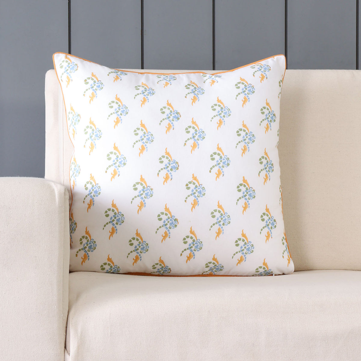 A swirl block-printed, combining orange, green, and blue on a white cotton cushion cover, displayed on the sofa, adds vibrancy to the living room decor
