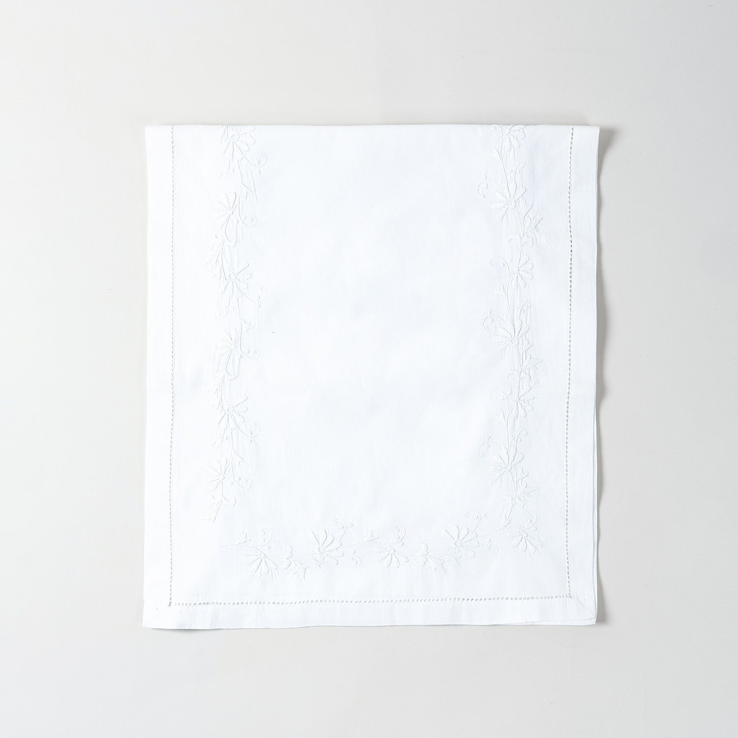 Folded white cotton table runner showcasing delicate white daisy embroidery and handcrafted Bengal chikankari detailing