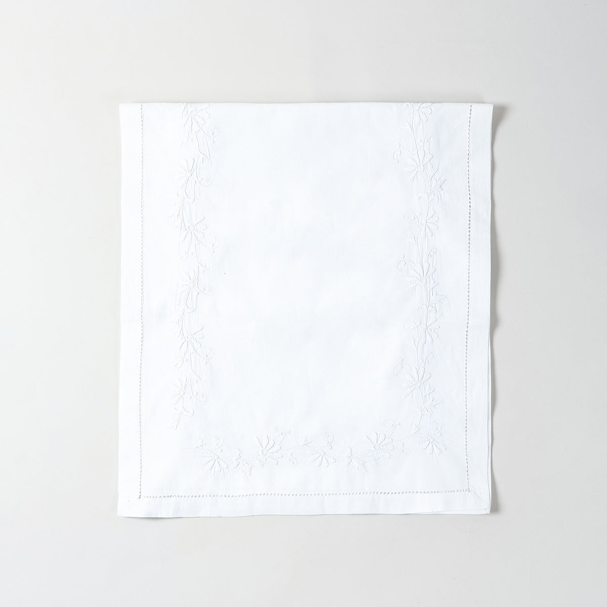 Folded white cotton table runner showcasing delicate white daisy embroidery and handcrafted Bengal chikankari detailing