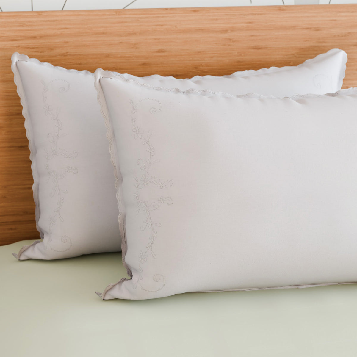 White floral vine embroidered pillow cases styled on a bed creating an elegant and serene bedroom setting
