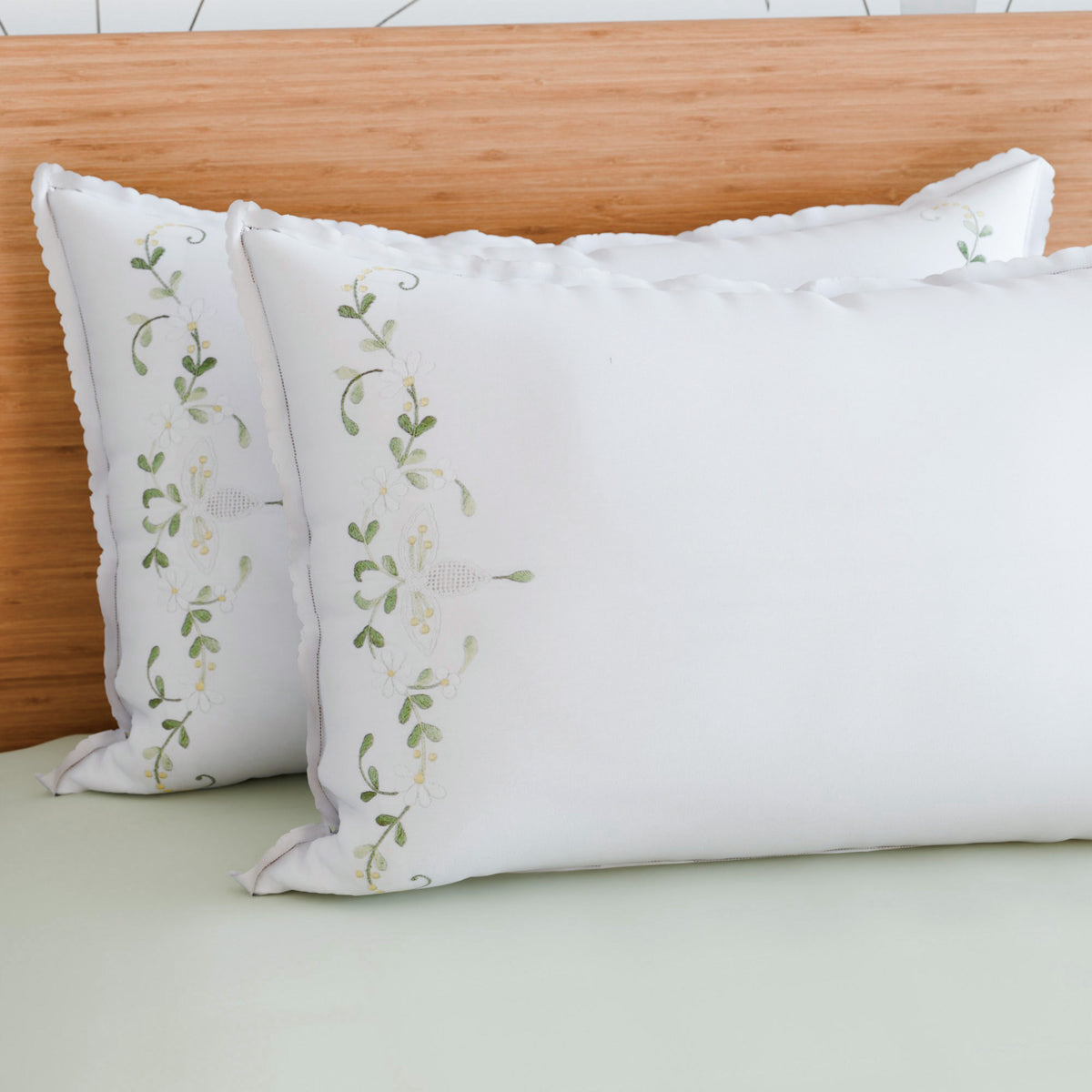 White and green chikankari embroidered pillow cases styled on a bed for fresh and calming bedroom decor