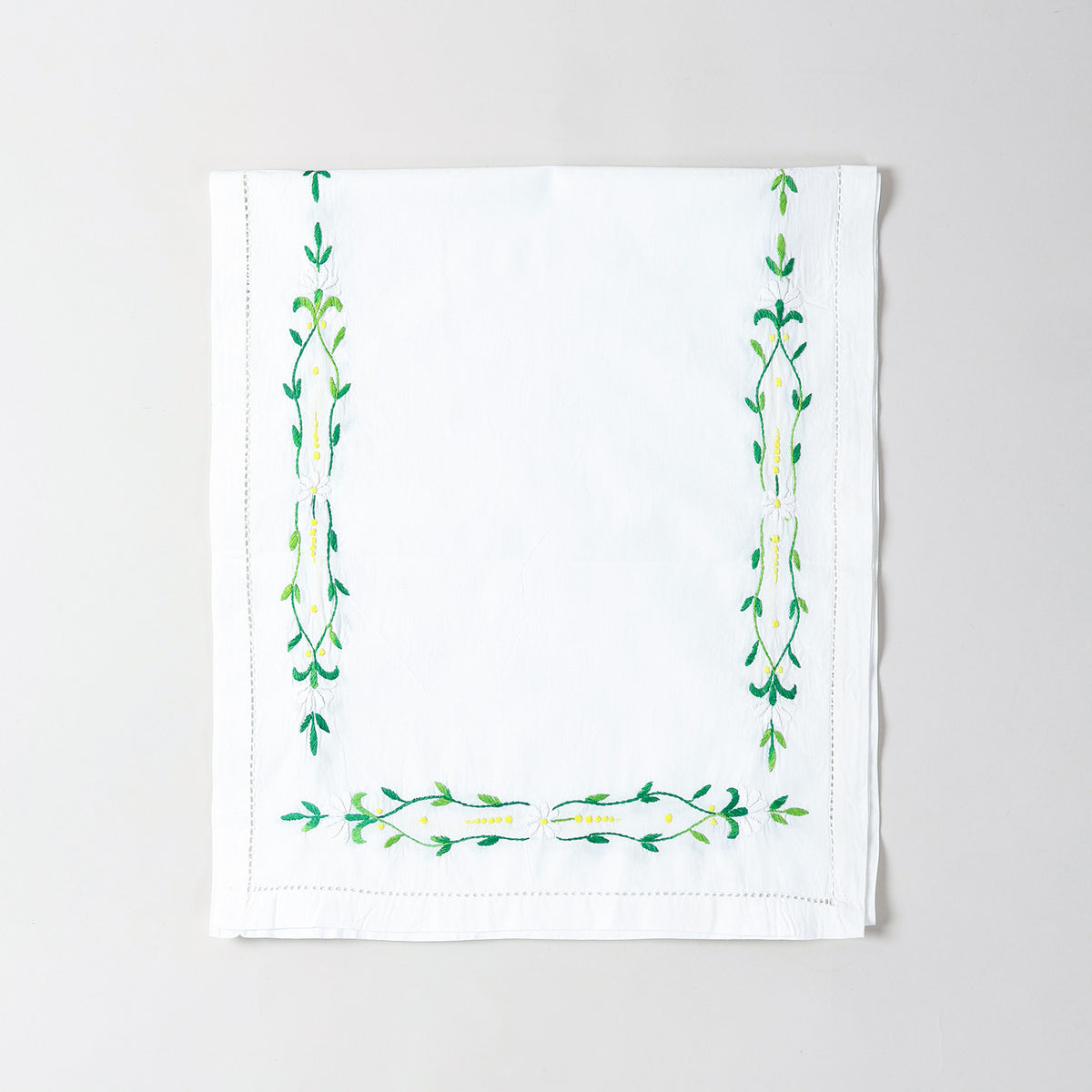  Folded Bengal chikankari runner showcasing green floral vine embroidery on soft white cotton table linen
